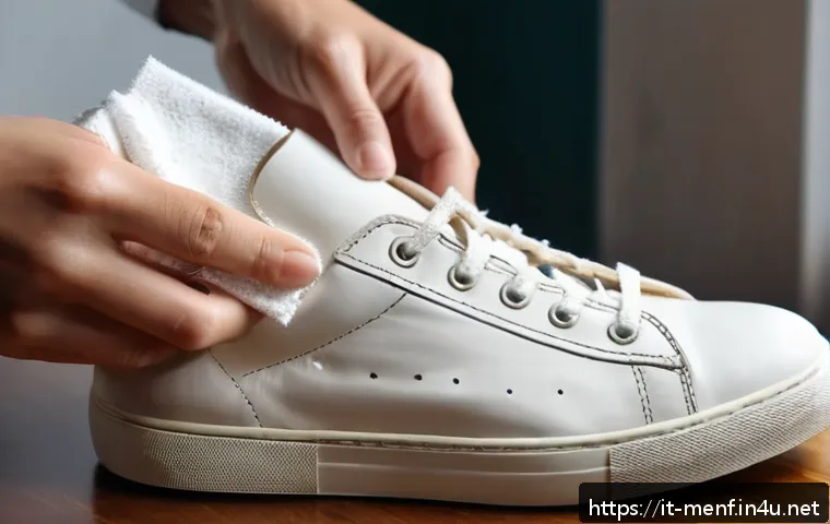 남성 스니커즈 관리 팁 - A close-up scene of hands gently cleaning a pair of white leather sneakers using a soft microfiber c...